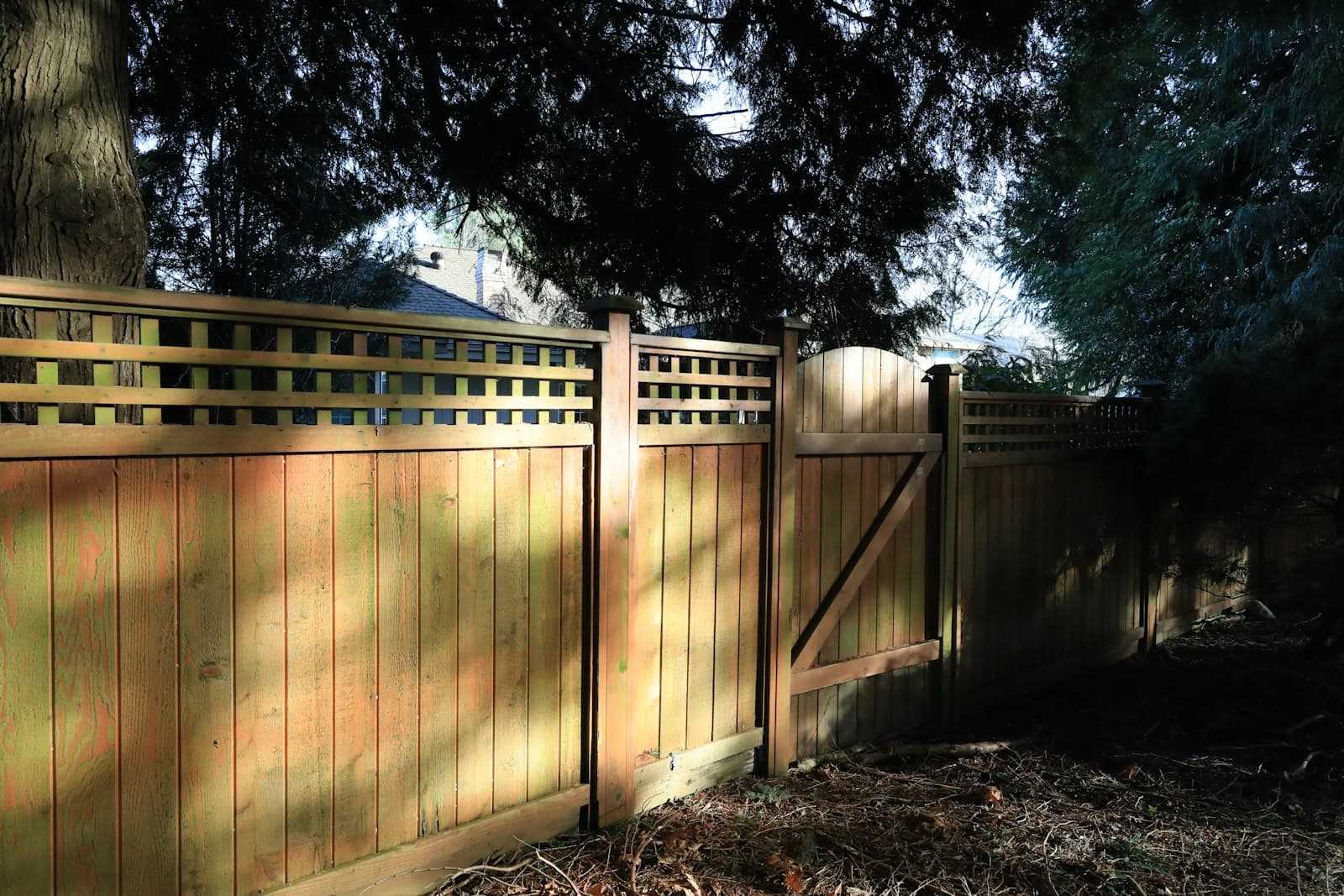 Residential wood privacy fence with an arched wood gate and lattice top