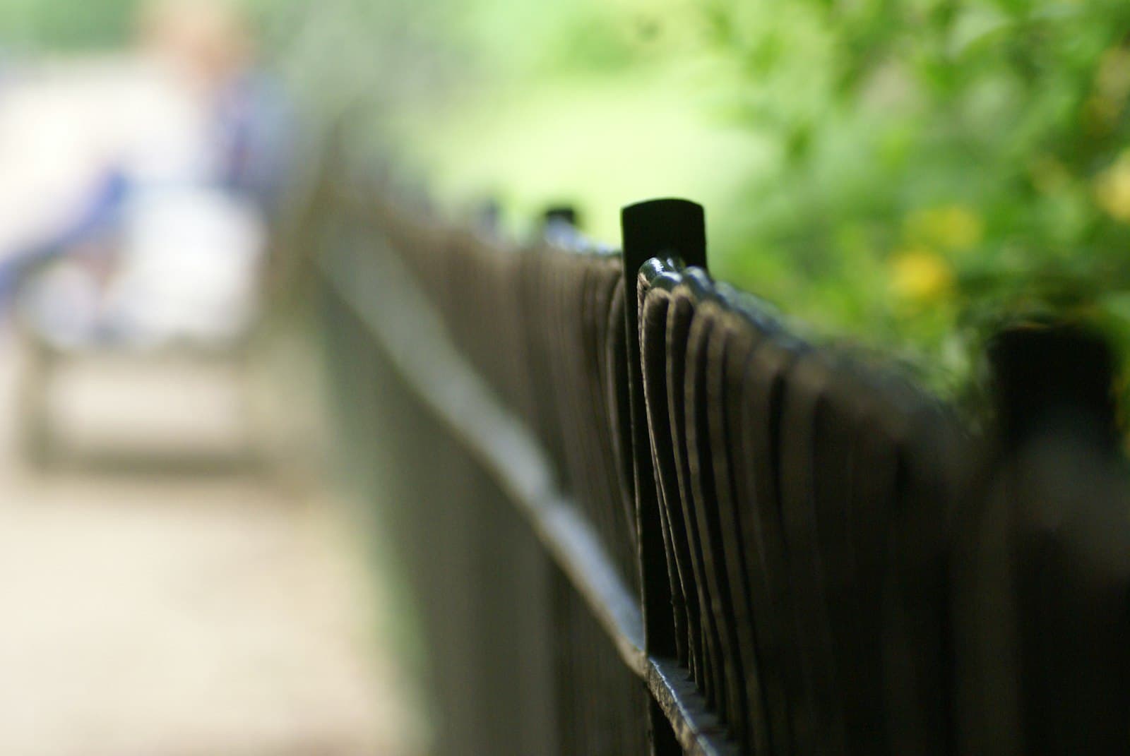 Black ornamental aluminum-style metal fence beside a path