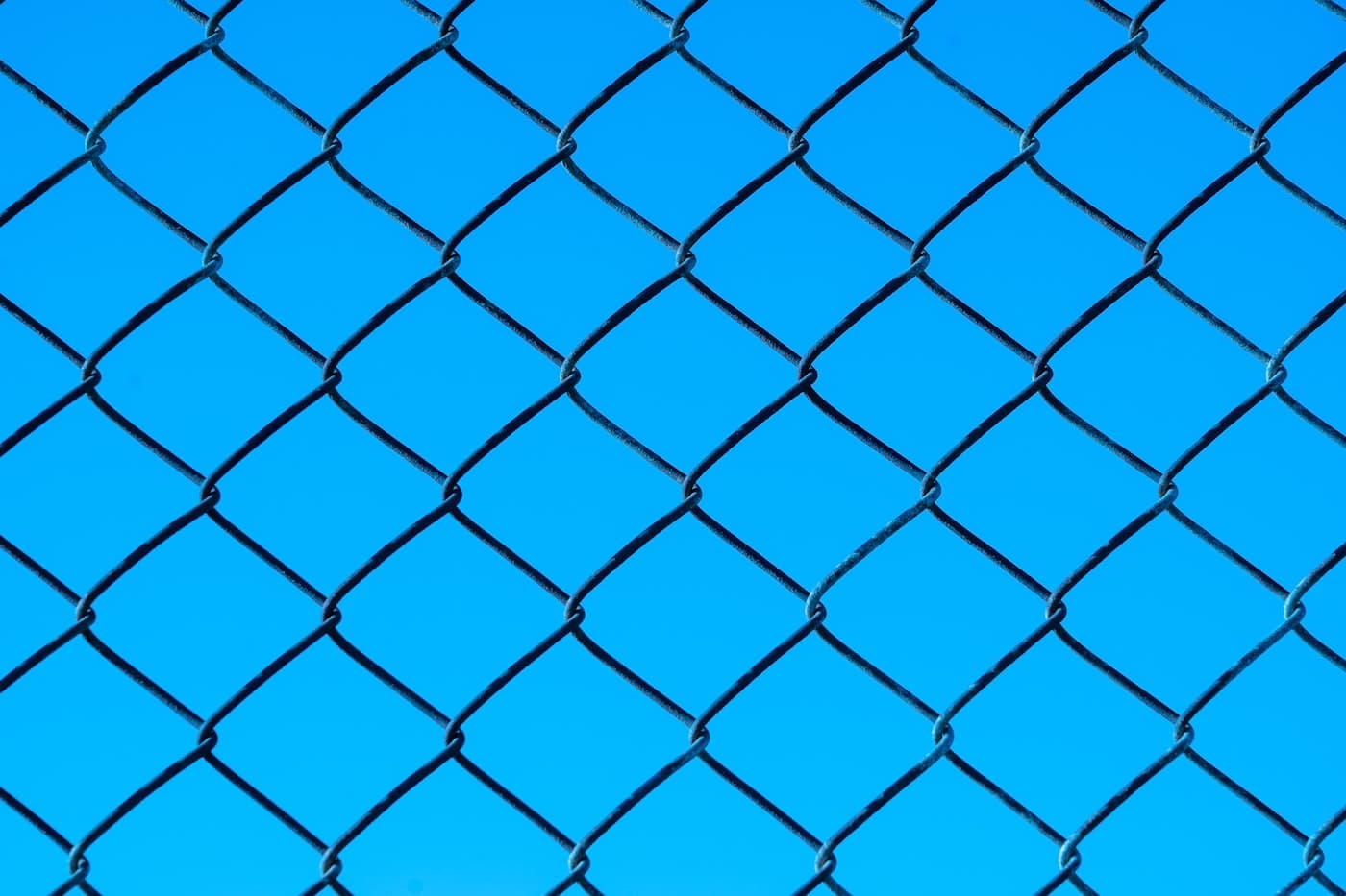 Close-up of a chain-link fence against blue sky